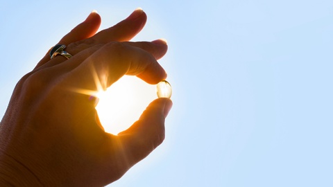 Eine Frau hält eine Vitamin-D-Kapsel ins Licht. © Shutterstock