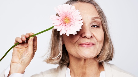 Symbolbild: Frau hält eine Blume in der Hand. © Shutterstock