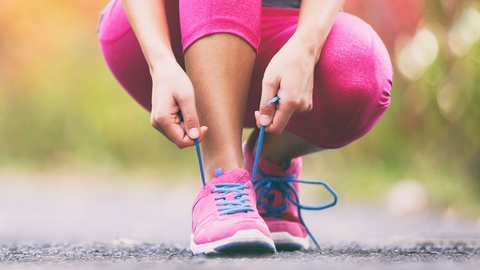 Symbolbild: Eine Frau bindet sich die Sportschuhe © Shutterstock