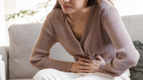 Eine Frau hält sich den Bauch. © Shutterstock