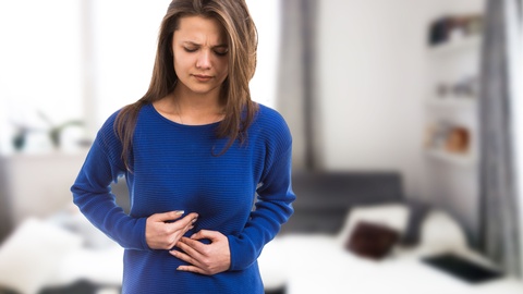 Eine Frau hält sich den Bauch. © Shutterstock