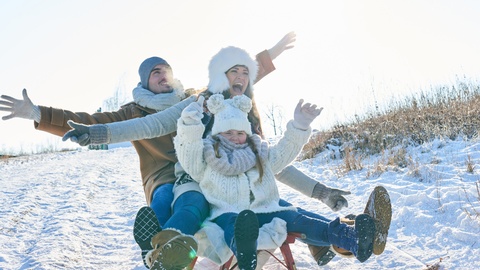 Eltern mit Kind auf einem Schlitten. © Shutterstock