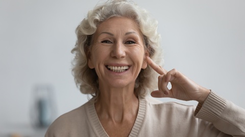 Eine Frau greift sich an das Ohr. © Shutterstock