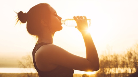 Junge, sportliche Frau trinkt aus Wasserflasche.  © Shutterstock