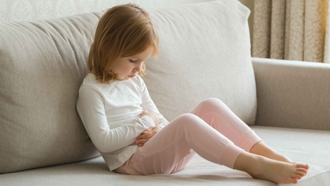 Kind mit Bauchweh sitzt am Boden  © Shutterstock