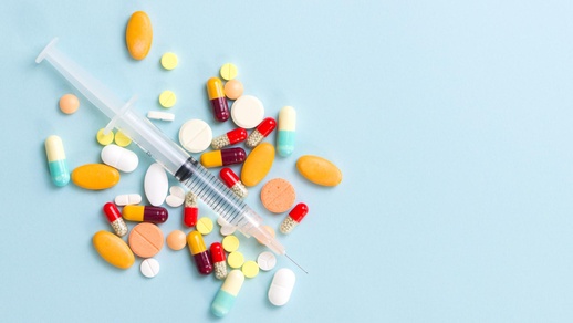 Spritze und Medikamente auf blauem Hintergrund © Shutterstock