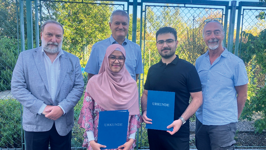 Preistr&auml;ger:innen 2025: Sharmin Shahabuddin (2. v.&thinsp;l.; mit ihrem Betreuer  Univ.Prof. Dipl. Ing. Dr. Manfred Ogris (h.&thinsp;l.)) und Aziz Ensar Tetik (2 v.&thinsp;r.)  erhalten ihre Preise vom Pr&auml;sidenten der &Ouml;PhG Univ.-Prof. i.R. Mag. Helmut Viernstein (l.) und Departmentsleiter Univ.-Prof. Mag. Dr. Thierry Langer (r.) im Arzneipflanzengarten der Universit&auml;t Wien.  &copy; beigestellt