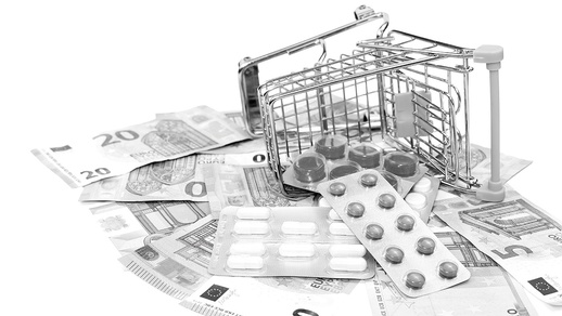 Geld und Tabletten fallen aus einem Einkaufswagen heraus. © Shutterstock