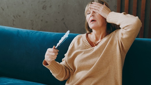 Frau sitzt auf dem Sofa und kämpft mit der Hitze. © Shutterstock