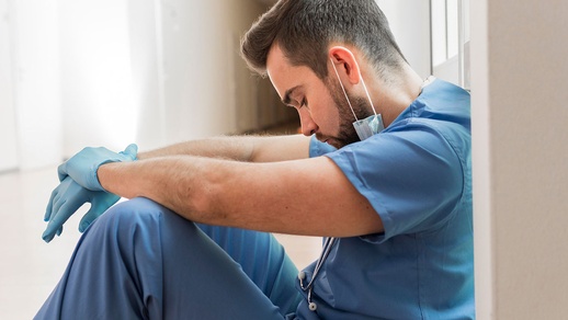 Pflegekraft ist erschöpft und sitz am Boden. © Shutterstock