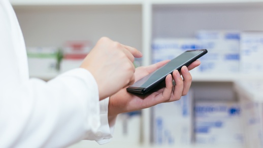 Ein Apotheker hält ein Smartphone in der Hand. © Shutterstock