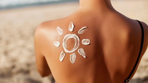 Eine Frau mit Sonnencreme auf dem Rücken. © Shutterstock