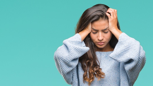 Eine Frau hält sich den Kopf und hat Kopfschmerzen. © Shutterstock
