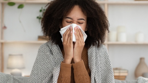 Eine Frau putzt sich die Nase mit einem Taschentuch. © Shutterstock