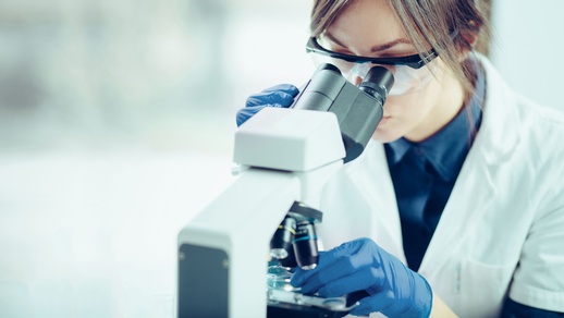 Symbolbild: Eine Frau blickt in ein Mikroskop. © Shutterstock