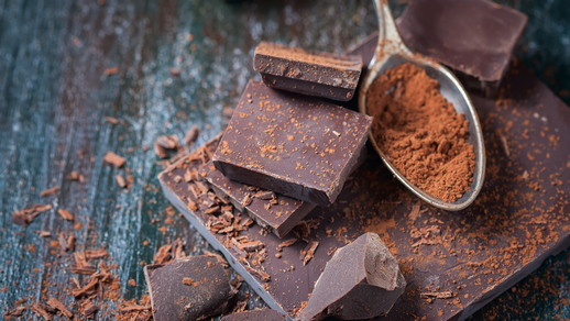 Mehrere Stücke dunkle Schokolade mit einem Löffel Kakaopulver.  © Shutterstock