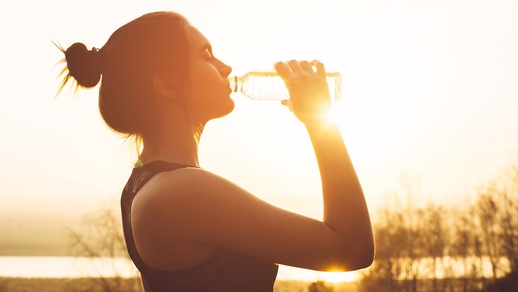 Junge, sportliche Frau trinkt aus Wasserflasche.  © Shutterstock