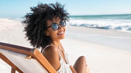 Eine Frau am Strand tr&auml;gt Sonnenbrille.  &copy; Shutterstock