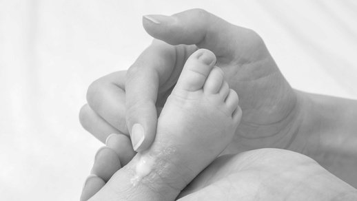 Mutter cremt Säugling am Bein ein © iStock