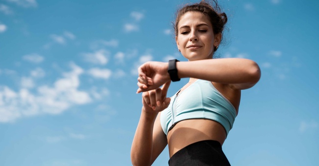 Frau trainiert und sieht auf die Uhr © Shutterstock