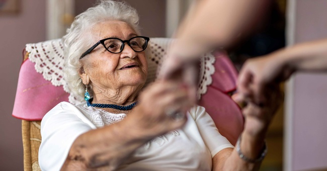 Pflegekraft reicht Demenzpatientin die Hände © Shutterstock