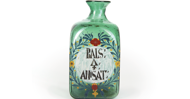 Ziergefäß aus grünem, mundgeblasenem Glas. Laut Beschriftung enthielt das Gefäß einst „Anishaltigen Schwefel- balsam“. Schwefel ist mit dem alchemistischen Zeichen angegeben. © HBF