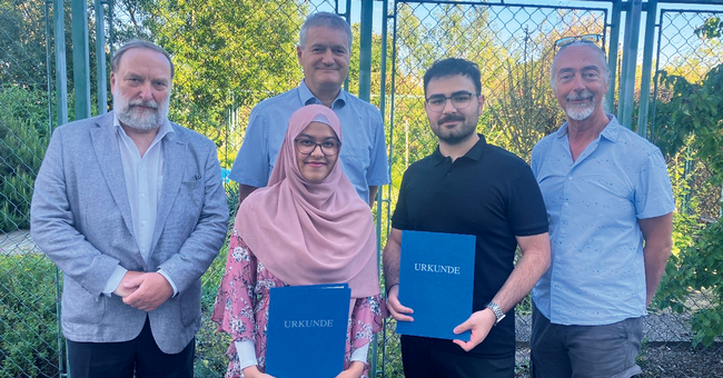 Preistr&auml;ger:innen 2025: Sharmin Shahabuddin (2. v.&thinsp;l.; mit ihrem Betreuer  Univ.Prof. Dipl. Ing. Dr. Manfred Ogris (h.&thinsp;l.)) und Aziz Ensar Tetik (2 v.&thinsp;r.)  erhalten ihre Preise vom Pr&auml;sidenten der &Ouml;PhG Univ.-Prof. i.R. Mag. Helmut Viernstein (l.) und Departmentsleiter Univ.-Prof. Mag. Dr. Thierry Langer (r.) im Arzneipflanzengarten der Universit&auml;t Wien.  &copy; beigestellt