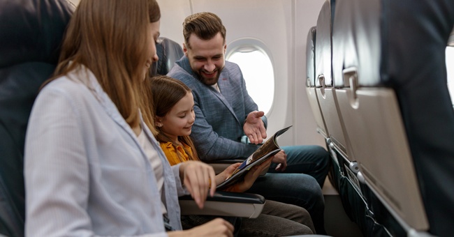 Eine Familie sitzt im Flugzeug. © Shutterstock