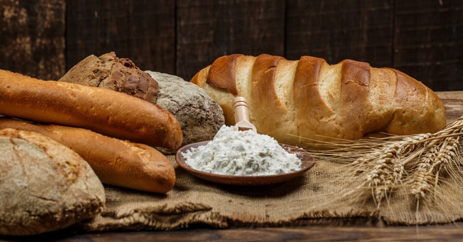 Frische Brotlaibe mit Weizen und Gluten auf einem Holztisch © Shutterstock