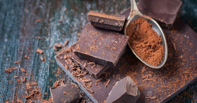 Mehrere Stücke dunkle Schokolade mit einem Löffel Kakaopulver.  © Shutterstock