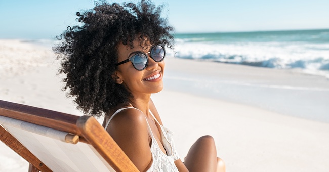 Eine Frau am Strand tr&auml;gt Sonnenbrille.  &copy; Shutterstock