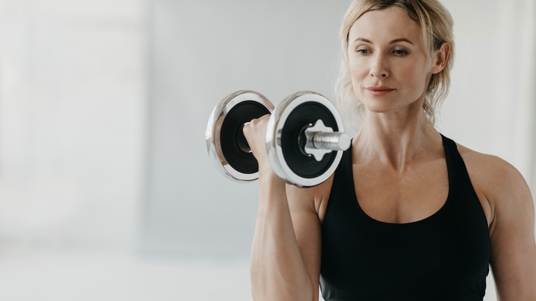 Eine Frau beim Krafttraining mit einer Hantel. &copy; Shutterstock