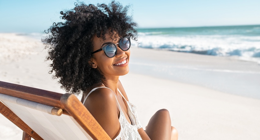 Eine Frau am Strand tr&auml;gt Sonnenbrille.  &copy; Shutterstock