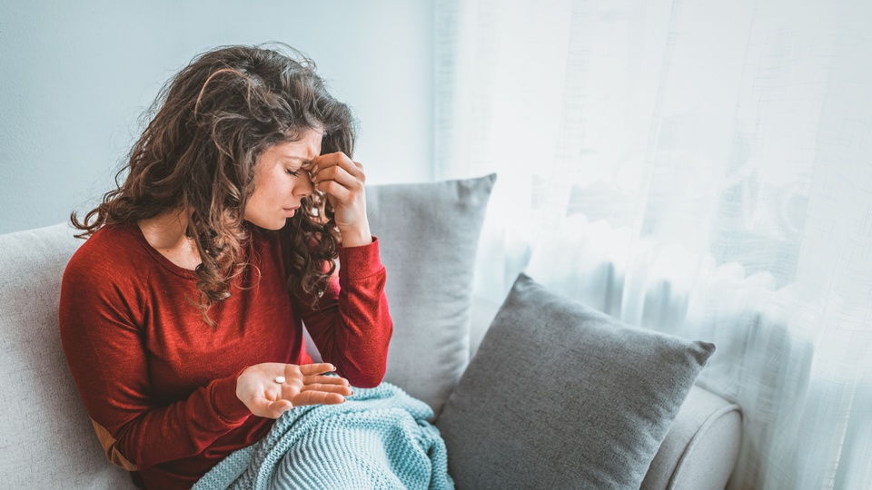 Eine Frau hat Kopfschmerzen und hält eine Tablette in der Hand. © Shutterstock