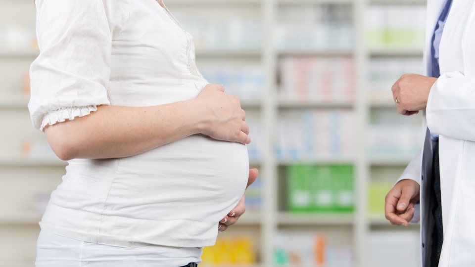 Eine schwangere Frau steht in der Apotheke © Shutterstock