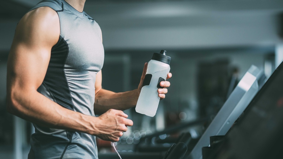 Ein trainierender Mann hält eine Wasserflasche in der Hand. © Shutterstock