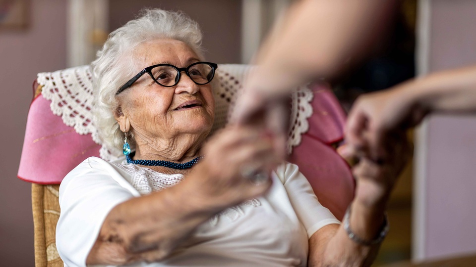 Pflegekraft reicht Demenzpatientin die Hände © Shutterstock